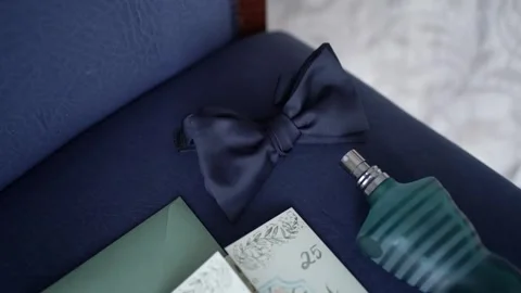 Bow tie perfume and invitation on suit fabric close up Stock-Footage 334632976