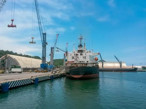 Bow view of loaded cargo ship sailing out of port. Stock Photos