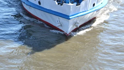 Bow of white and blue ship navigating river water, creating wake and shadows Stock Footage 344697010