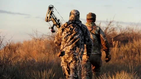 Bowhunters walking through the brush looking for dear Stock Footage 171996573