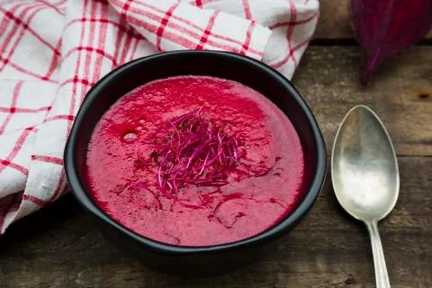 Bowl of beetroot soup garnished with beetroot sprouts on dark wood Stock Photos
