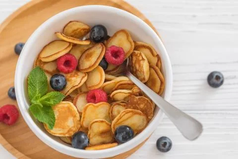 Bowl for breakfast with tiny pancake cereal with blueberries, raspberries, mi Stock Photos
