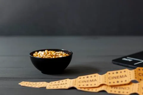 Bowl with corn kernels, next to a clapperboard on a black wooden background Stock Photos