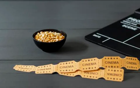 Bowl with corn kernels, next to a clapperboard on a black wooden background Stock Photos