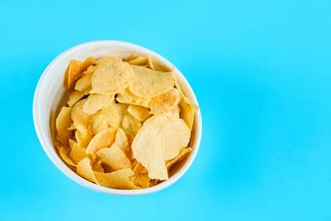 Bowl of crispy chips on blue background Stock Photos