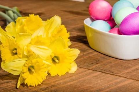 Bowl of dyed Easter eggs with daffodils Stock Photos