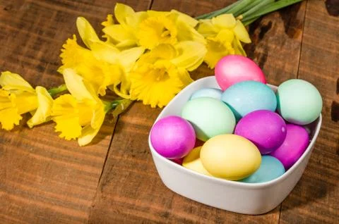 Bowl of dyed Easter eggs with daffodils Stock Photos