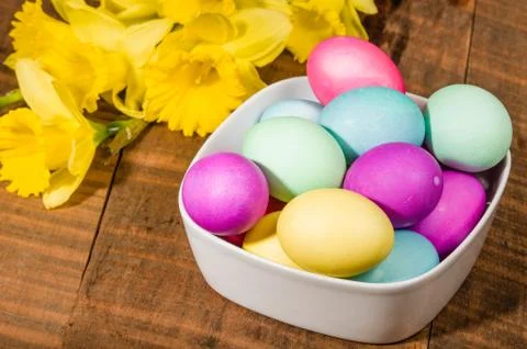 Bowl of dyed Easter eggs with daffodils Stock-Fotos