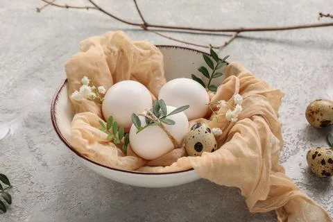 Bowl with Easter eggs, leaves and beautiful gypsophila flowers on grey backgr Stock Photos