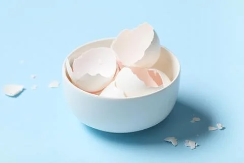 Bowl with egg shells on blue background Foto stock