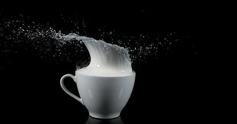Bowl with Exploding Milk against Black Background Stock Photos