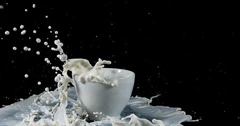 Bowl with Exploding Milk against Black Background Stockfoto's