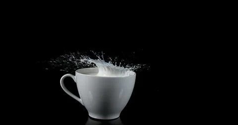 Bowl with Exploding Milk against Black Background Stockfoto's