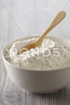 A Bowl Of Flour With A Wooden Spoon