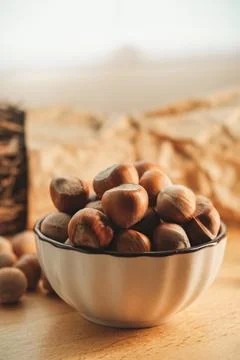 Bowl of fresh hazelnuts surrounded by rustic natural decor Stock Photos