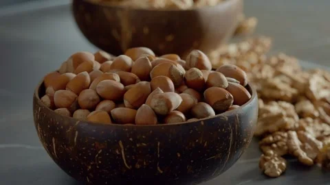 Bowl of hazelnuts with walnut kernels nearby for healthy snacking options Stock Footage 327582144