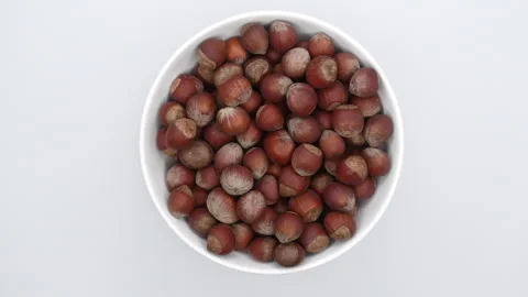 A Bowl Of Hazelnuts On A White Background Rotates. Extreme Close Up. Top View. Stock Footage 249662956