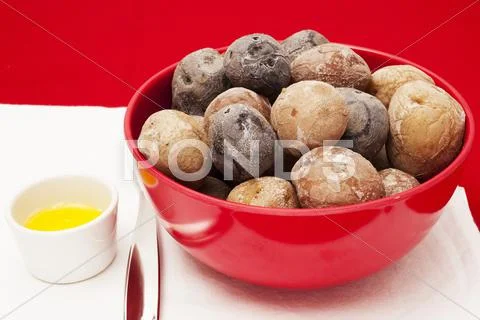 A bowl of jacket potatoes and a dish of butter Stock Photos