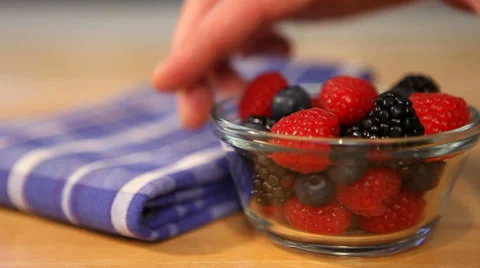 Bowl of mixed berries put down by hand Stock Footage 33580827