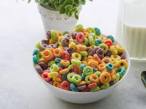 Bowl with multi-colored grain fruit rings, milk in a jug and decor - indoor f Stock Photos