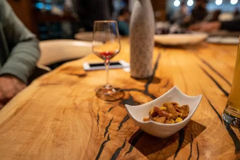Bowl of nuts next to empty wine glass on wooden restaurant table Stock Photos