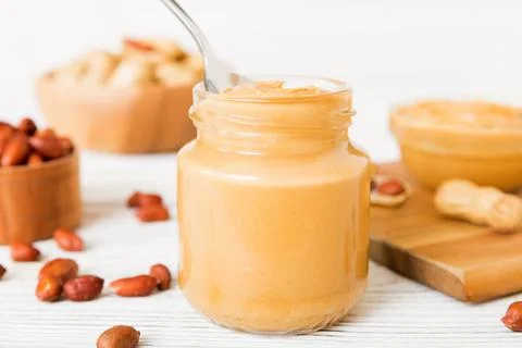 Bowl of peanut butter and peanuts on table background. top view with copy spa Stock Photos