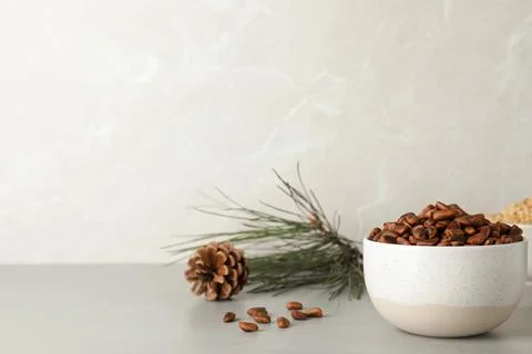 Bowl with pine nuts on table against light background. Space for text Foto stock