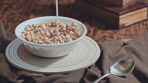 Bowl of puffed wheat cereal filled with milk on a rustic wooden table Vídeo Stock 335894992