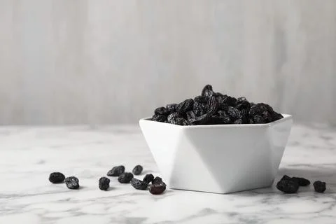 Bowl with raisins on marble table, space for text. Dried fruit as healthy sna Stock Photos