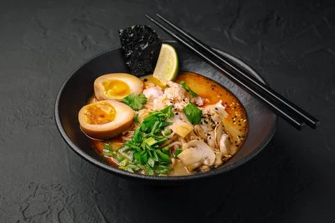 A bowl of ramen sits on a dark table Stock Photos