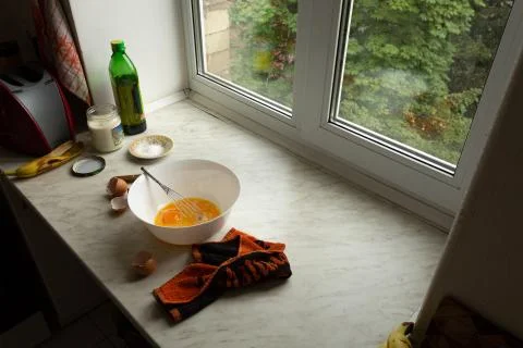 Bowl of raw eggs on the kitchen table by the window, top view Photos