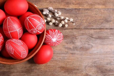 Bowl with red painted Easter eggs on wooden background, top view. Space for t Stock Photos