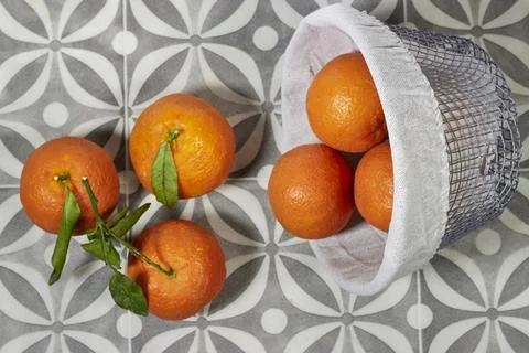 Bowl of ripe mandarin sits on a patterned tile surface with a few extra oranges  Stock Photos