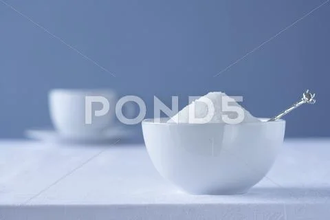 Bowl of sugar on table tea cup in background Stock Photos