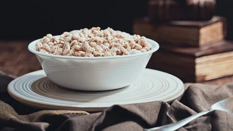 Bowl of wheat cereal with milk on a rustic table with a background of old books. Stock-Footage 335895408