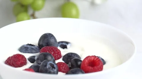Bowl of white yogurt with with raspberry and blueberry, top view, rotation... Stock Footage 268276011