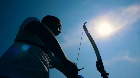 Bowman is pulling the bowstring in the sunlight. Shooting with a bow and arrows. Stock Footage 113453619