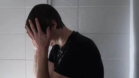 Bows his head under running shower water student in wet black shirt showing exha Stock Footage 315991734