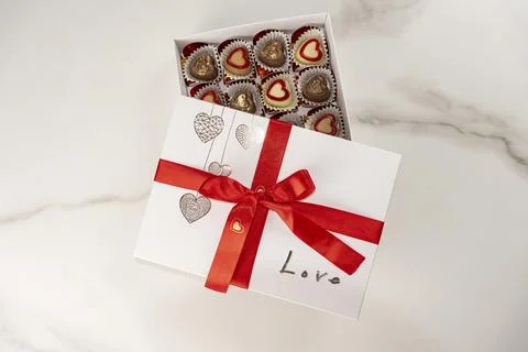 Box of assorted chocolates with the lid open and a red bow top view. Stock Photos