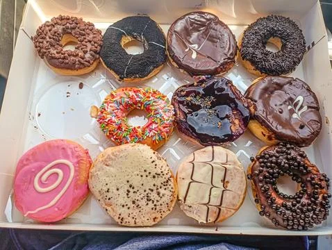 Box of assorted donuts with chocolate, sprinkles, and icing. Sweet treats f.. Stock Photos