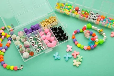 Box with beads to create hand made jewelry for child on mint background. Ma.. Stock Photos