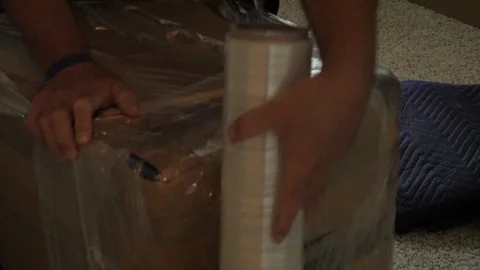 Box Being Wrapped Plastic Wrap Dark Room Handheld Shot Stock-Footage 129499655