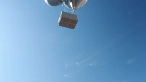 Box with big silver balloons flies down against blue sky Stockbeeldmateriaal 171291435