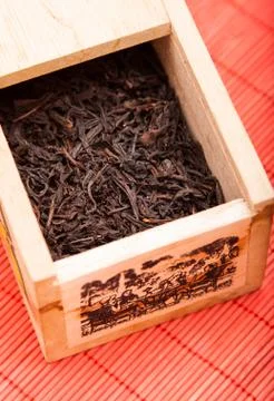 Box with black tea on red mat Stock Photos