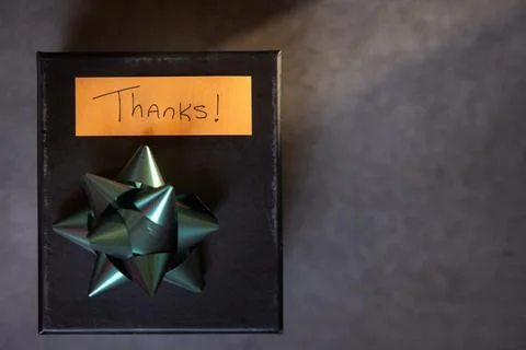 A box with a bow on top and a note that says "Thanks" written on it Stock Photos