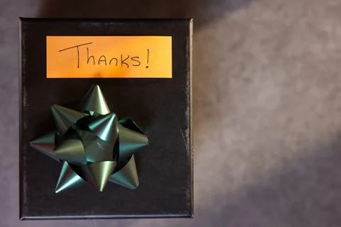 A box with a bow on top and a note that says "Thanks" written on it Stock Photos