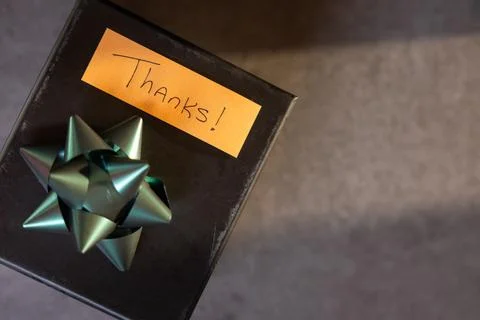 A box with a bow on top and a note that says "Thanks" written on it Stock Photos