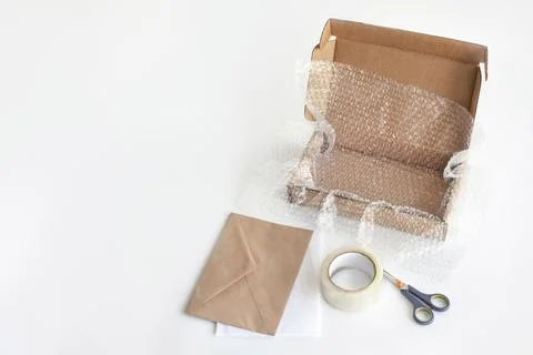 Box, bubble wrap, tape, scissors, paper envelope. Product packaging concept Stock Photos