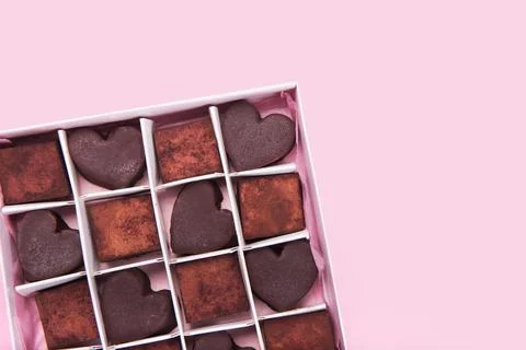 Box with chocolate heart shaped sweets on pink background. Valentine Day concept Stock Photos