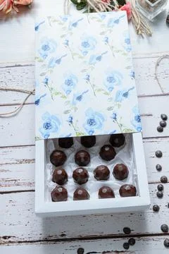 Box with chocolates on a white table, next to twine rope and chocolate callet Stock Photos